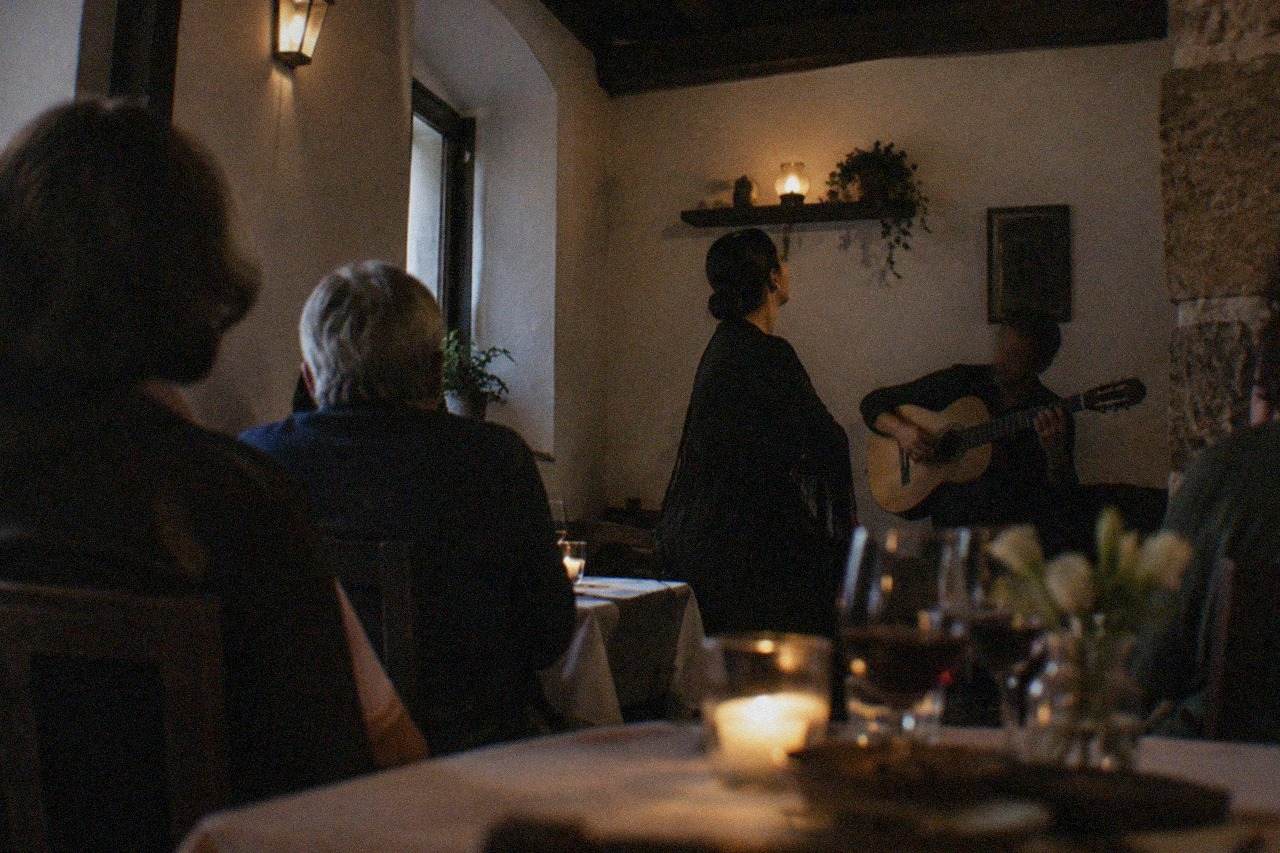 A fado singer performing in a dimly lit room in Coimbra while diners listen quietly