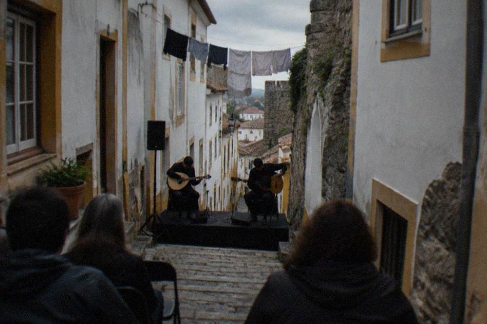 Two Portuguese guitar players tuning instruments on a small stage before a fado performance