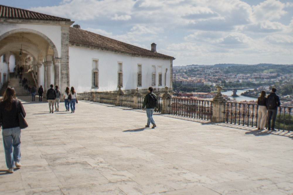 Students and visitors walking through the stone arches and stairways of the University of Coimbra hill