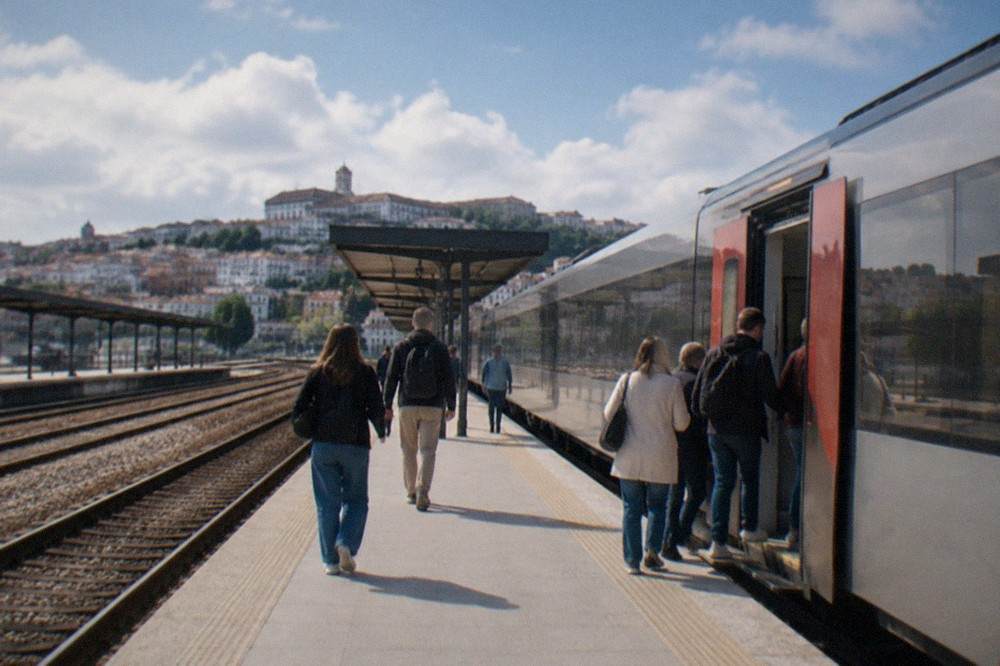 A rail platform in Coimbra with a train waiting and passengers boarding