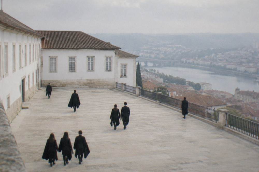 Students in black capes walking through the old university courtyard in Coimbra