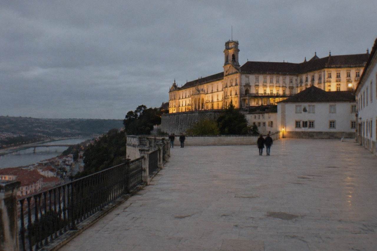 The floodlit Royal Palace of the University of Coimbra seen from below at dusk