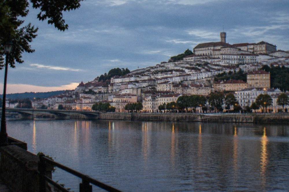 The hillside city of Coimbra seen from across the River Mondego with the university buildings above the rooftops