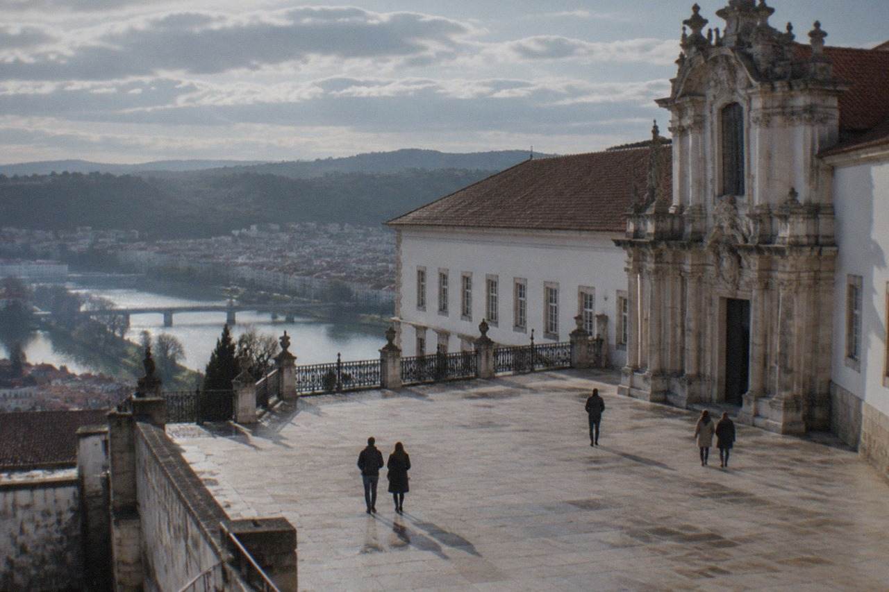 The ornate baroque facade and terrace of the University of Coimbra buildings above the city rooftops