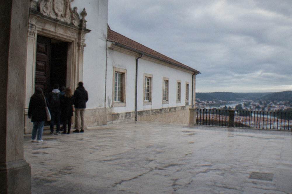 Visitors waiting at an ornate carved wooden door inside a historic university building