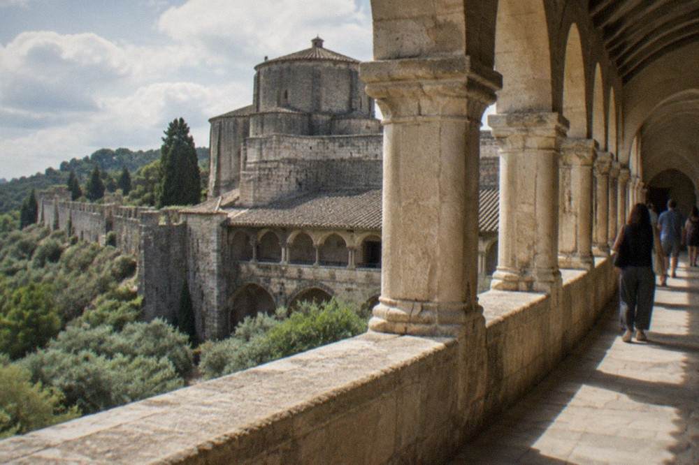 Visitors walking through the stone cloister arcade of the Convent of Christ in Tomar