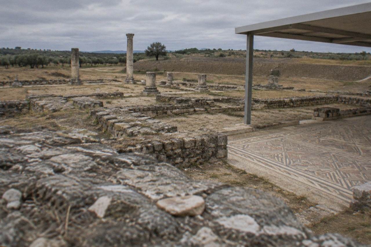 Roman stone walls and column bases of the Conimbriga ruins under an open sky