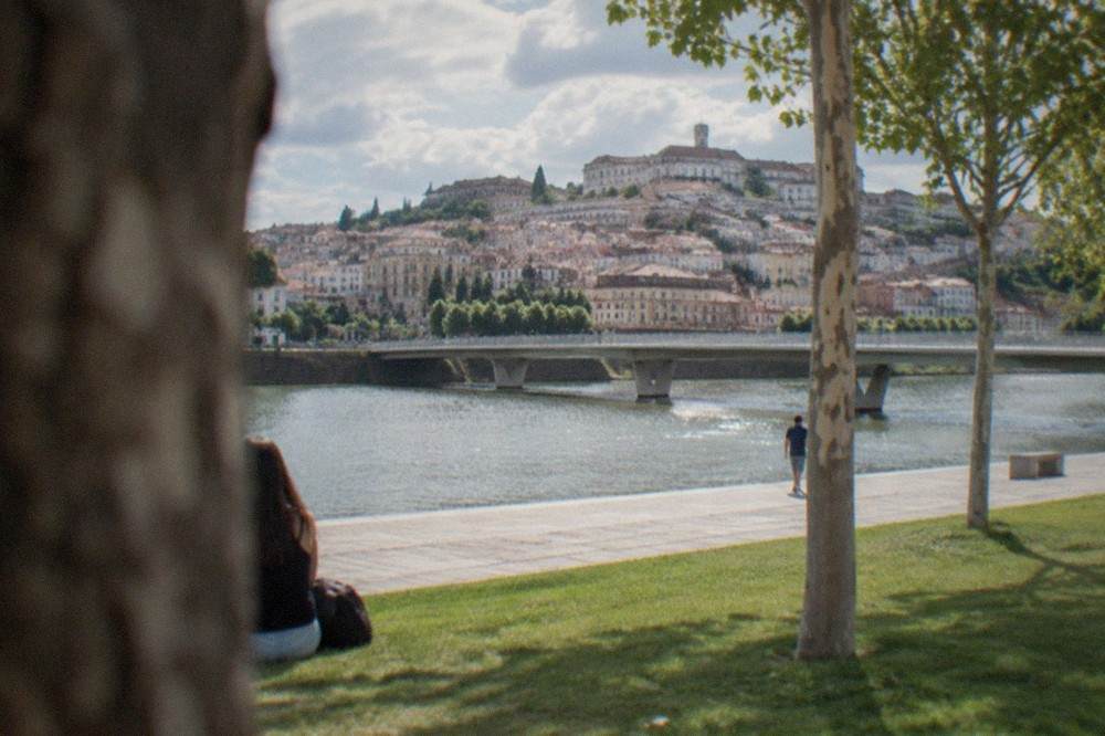 The Mondego riverfront of Coimbra with the old bridge and the university hill behind