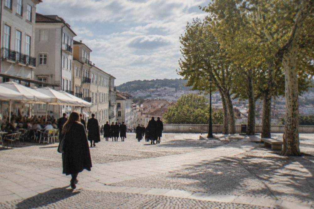 Students in black capes walking down the cobbled lane below the university hill in Coimbra