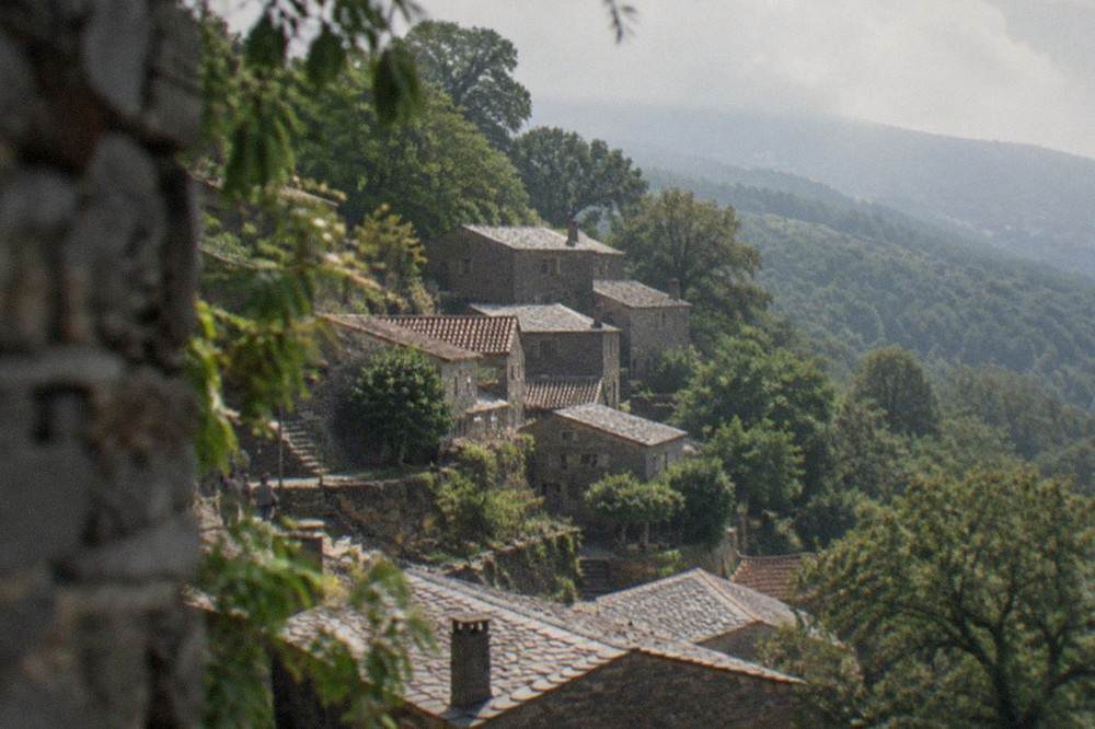 A stone schist village terrace on the Lousã mountain, with slate-roofed houses among trees.