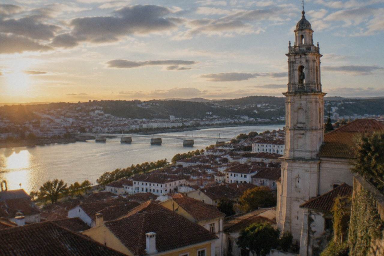 Evening view over the tiled rooftops of Coimbra old town with the university tower lit above the River Mondego