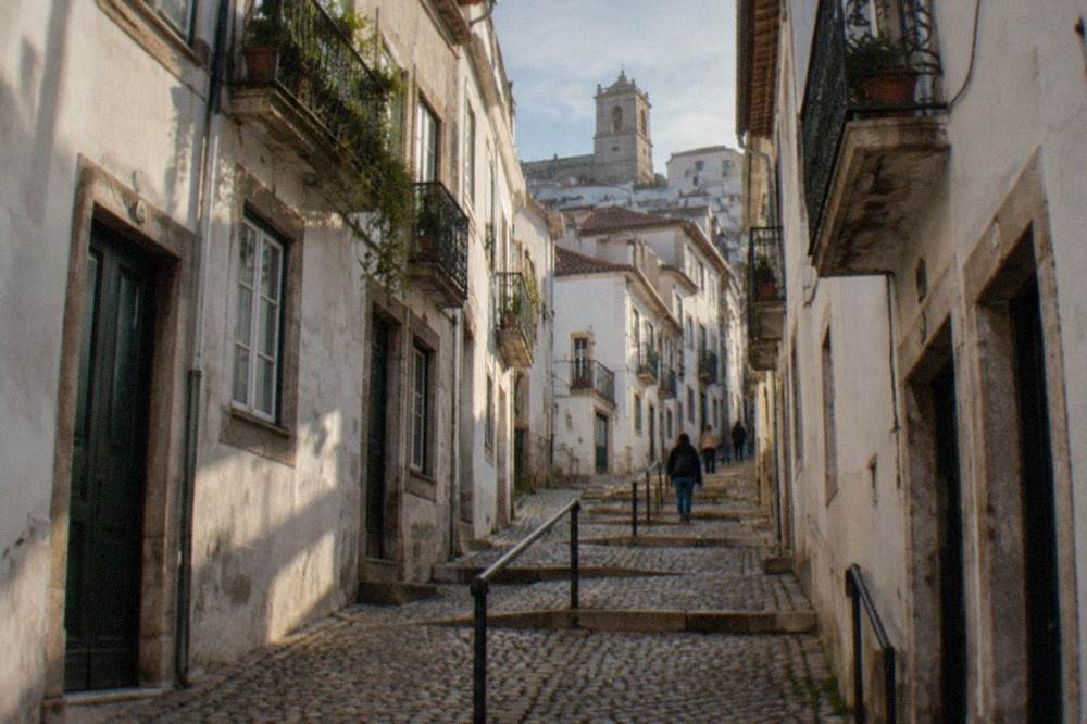 Narrow cobbled street climbing through the old upper town of Coimbra