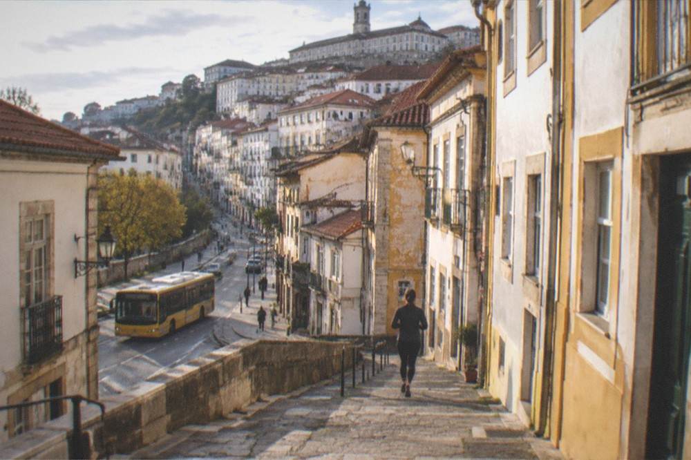 Yellow city bus on a street in central Coimbra with old buildings behind