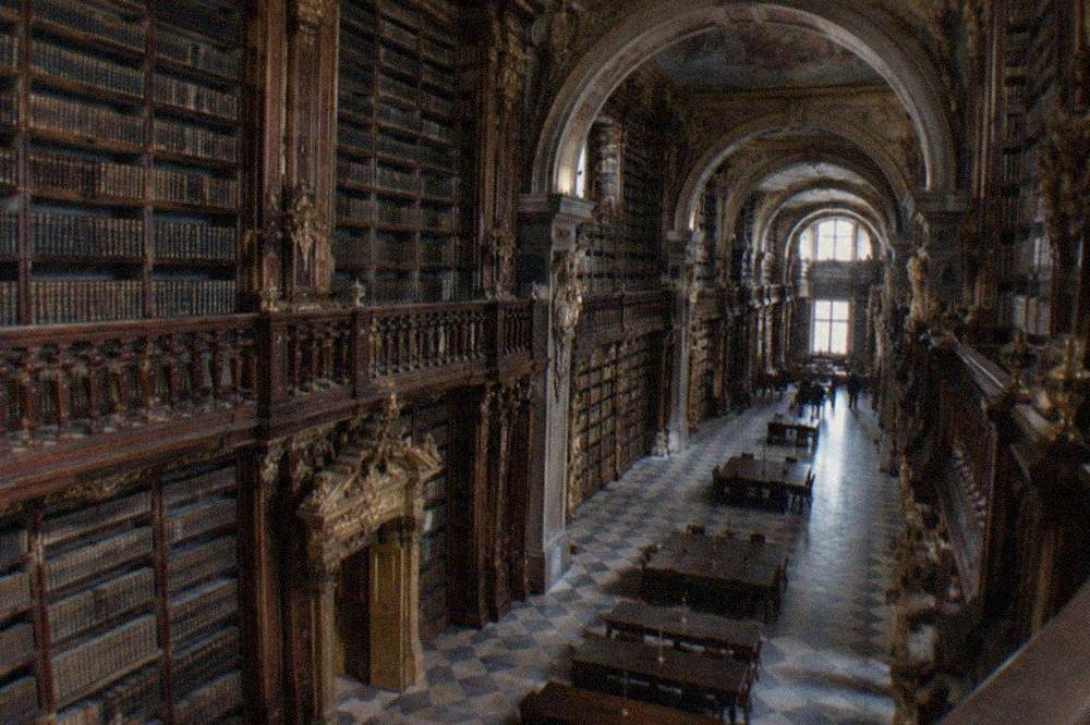 A gilded doorway and carved bookshelves inside the Joanina Library in Coimbra