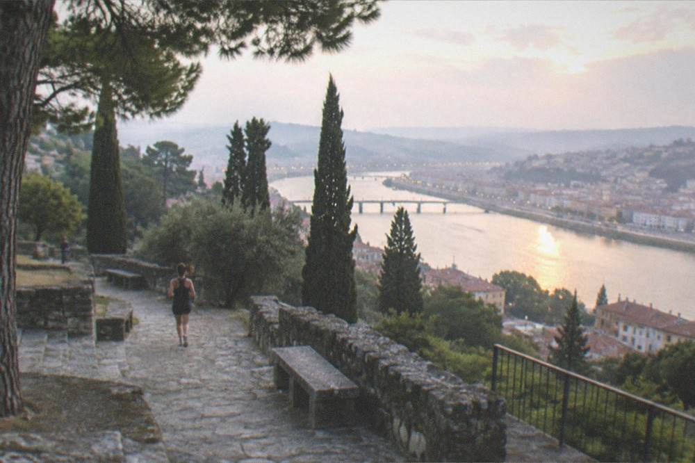 The terrace railing and the river at dusk with city lights beginning to appear on the far bank
