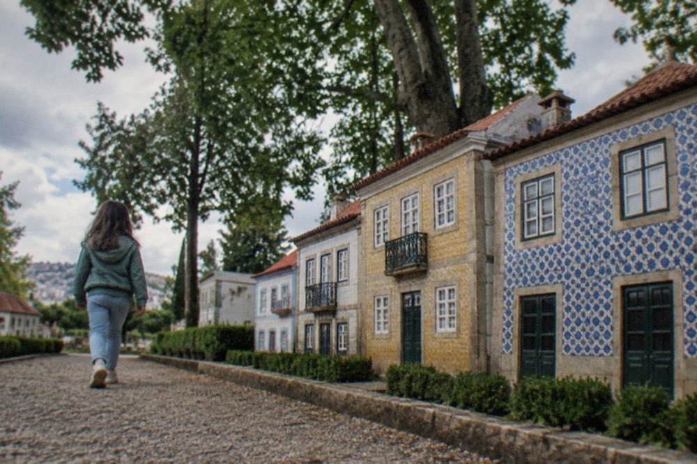 A child walking past a row of miniature regional Portuguese houses with tiled facades