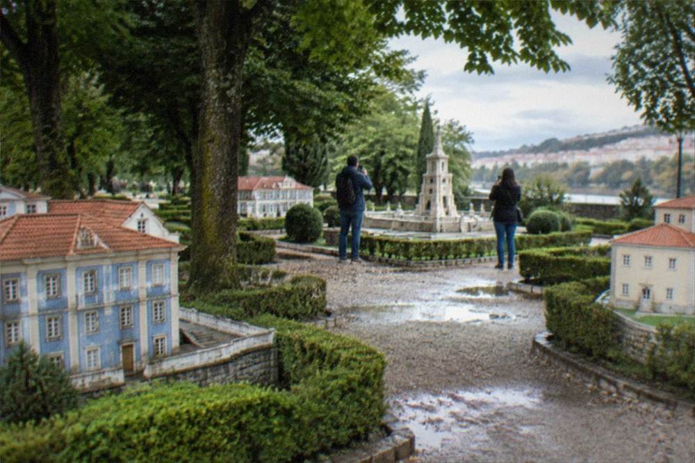 A miniature monument with visitors photographing it from a path
