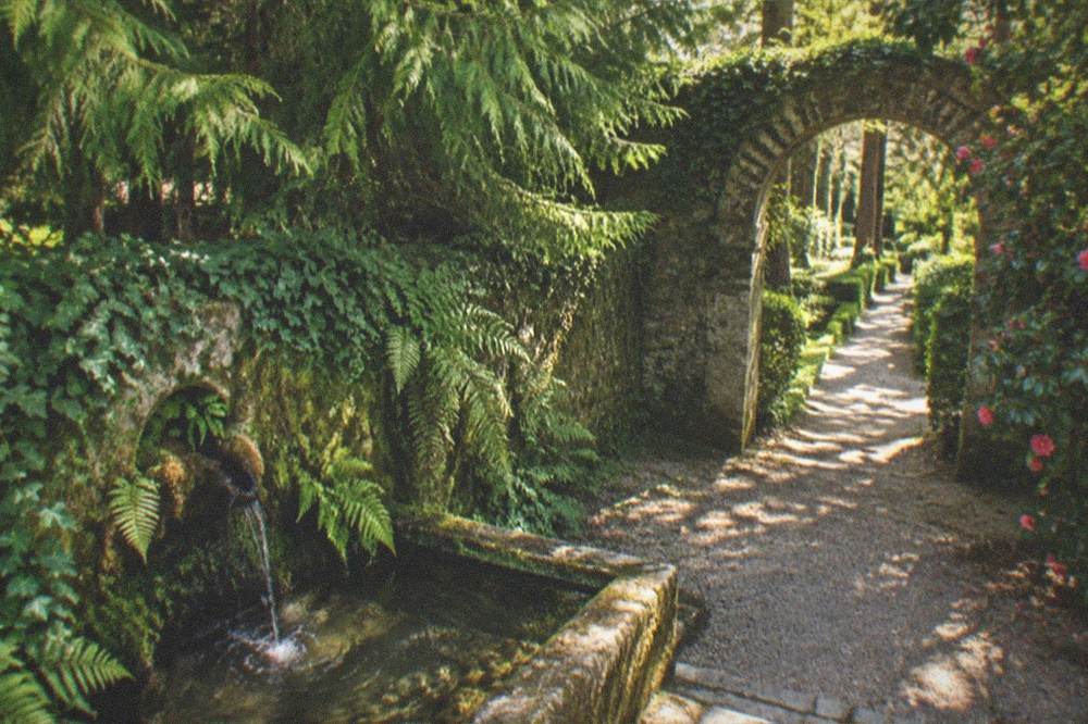 Stone archway and green garden corridor inside a historic estate at golden hour