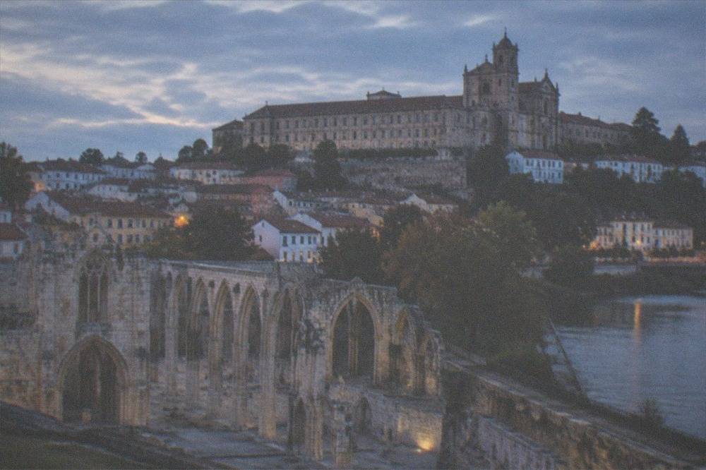 A large stone convent building with a church facade standing on a hilltop above rooftops