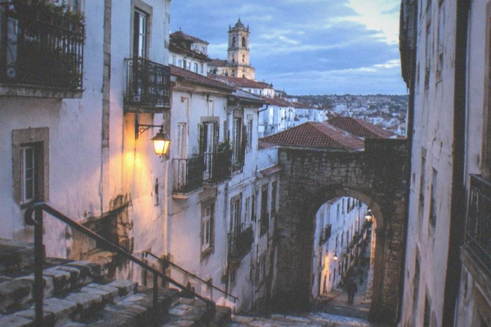 A stone gate arch leading from the upper town down a narrow old street towards the lower town