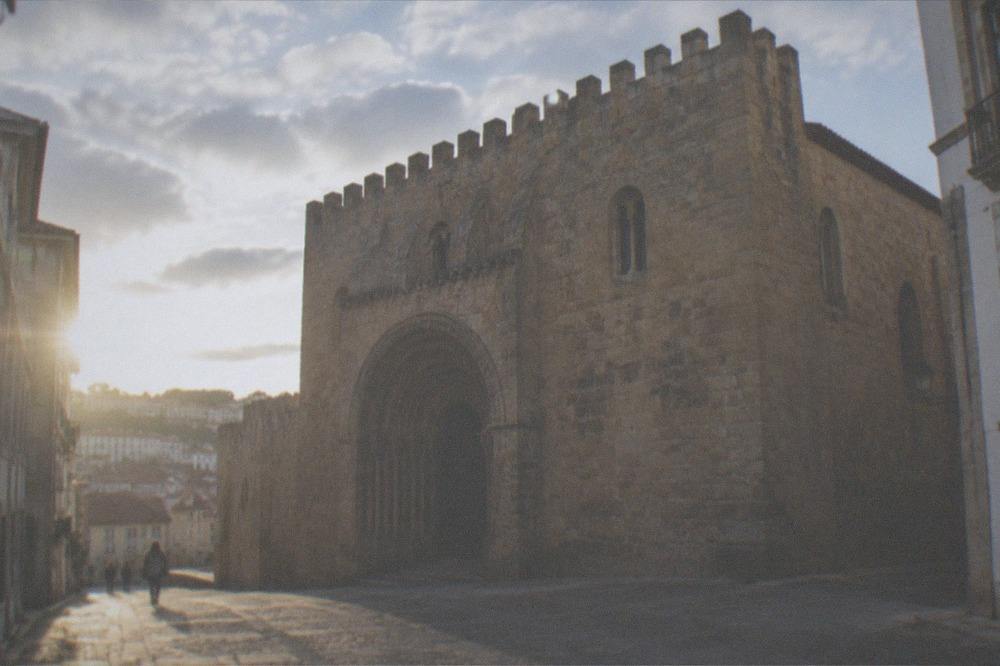 The stone portal of the old cathedral of Coimbra with its carved archway in shadow