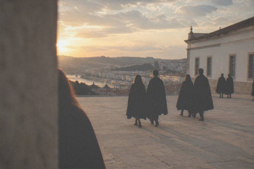 Students in black capes crossing the stone courtyard of the Paço das Escolas in Coimbra