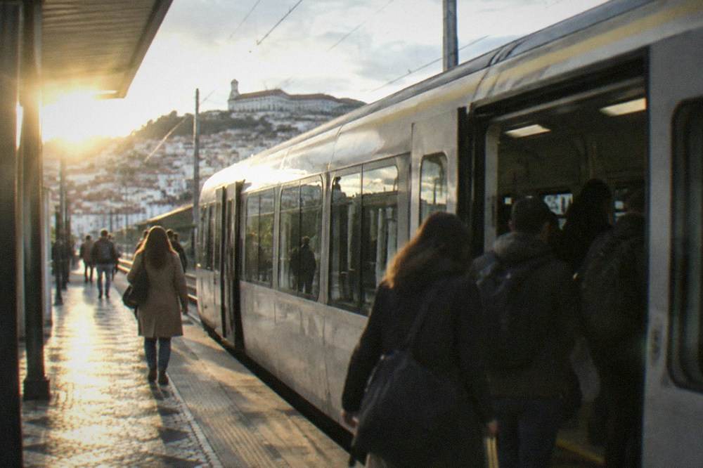 A regional train standing at a Portuguese station platform with passengers boarding