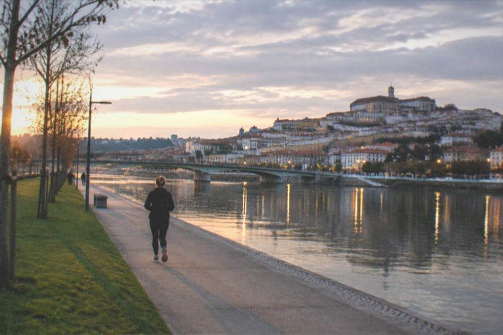 The River Mondego at dusk with the lights of Coimbra's old town reflected in the water