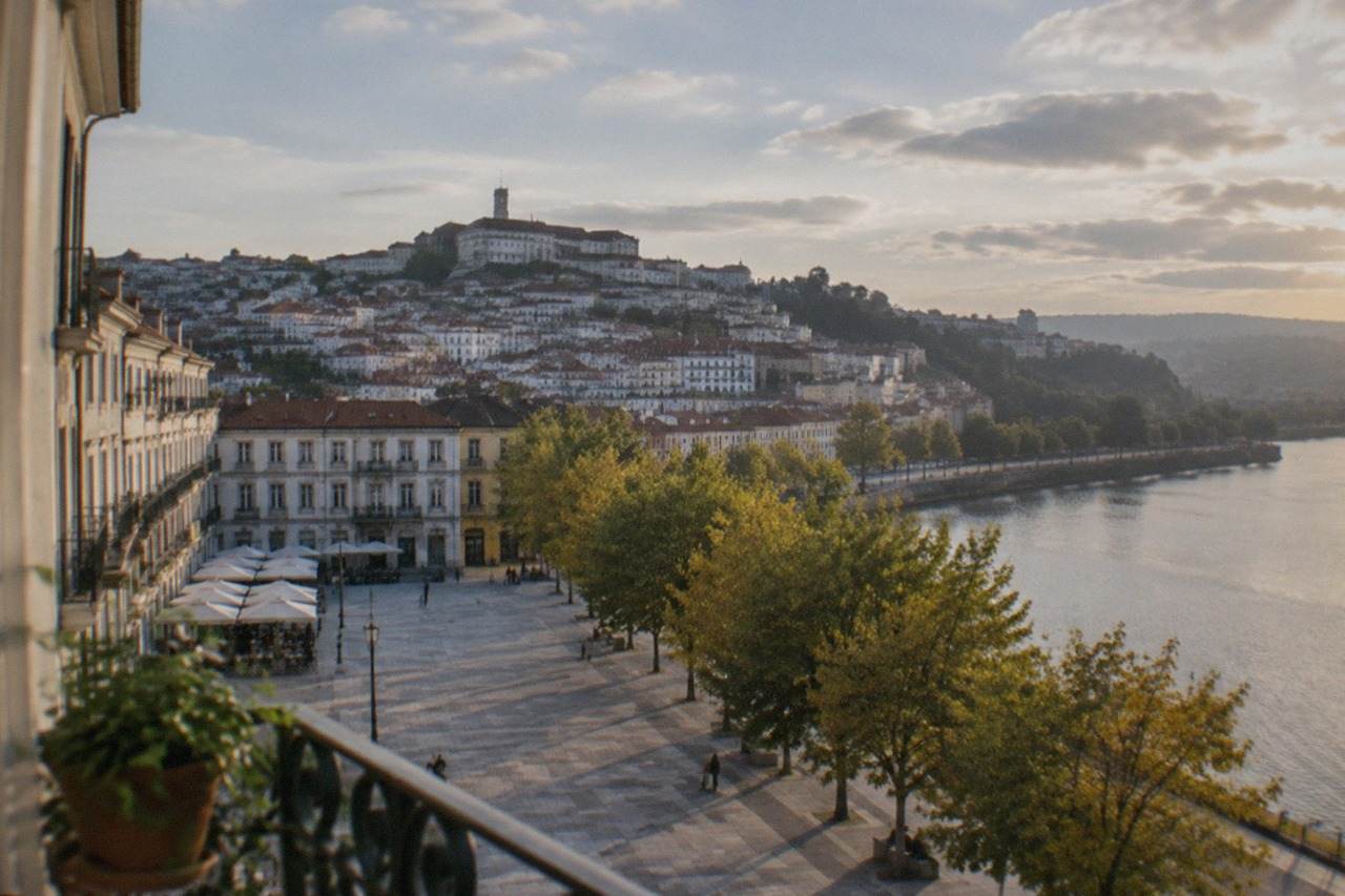 View over the tiled roofs and university hill of Coimbra, Portugal, from a riverside apartment balcony