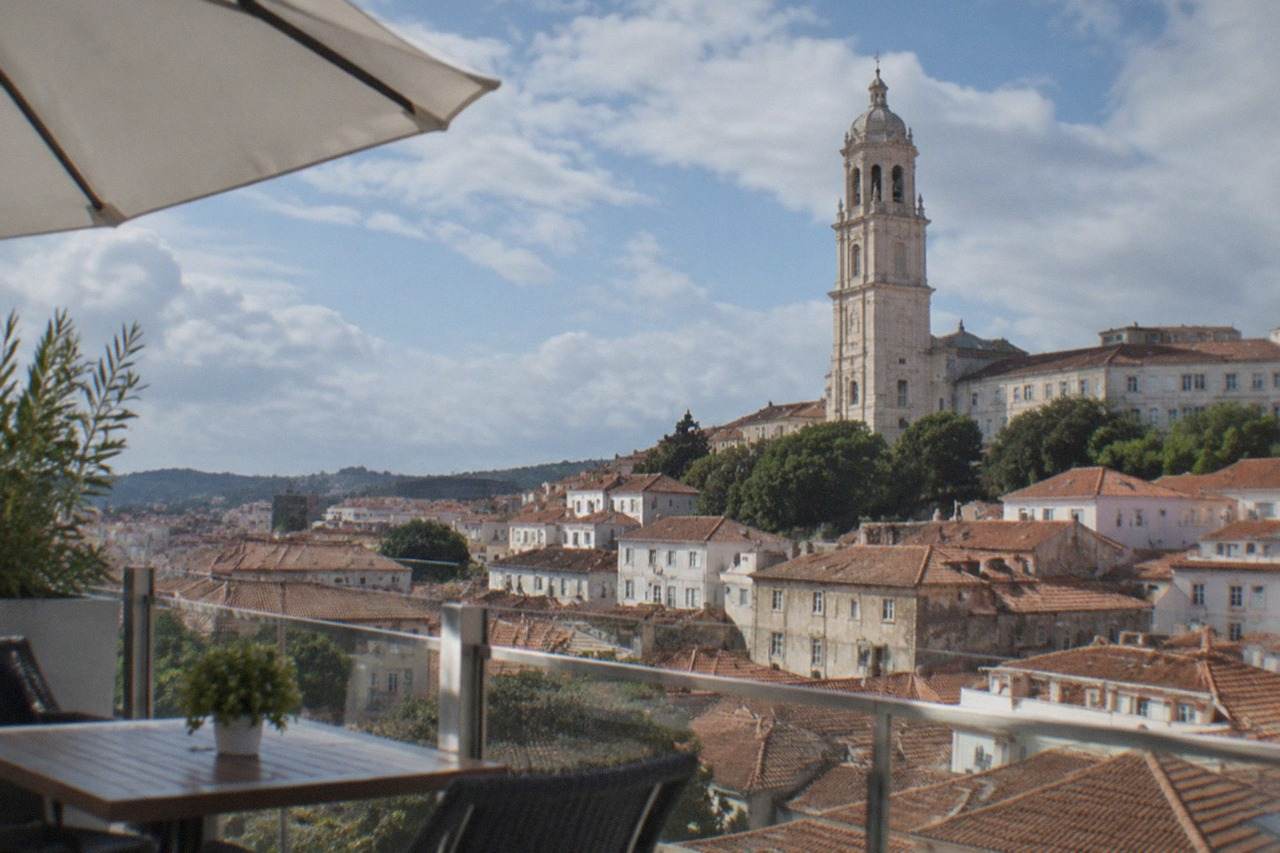 Hotel terrace overlooking the rooftops of Coimbra with the university tower above the old town