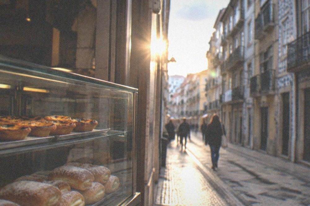 A glass pastry case filled with small egg sweets and sugar-dusted rolls in an old café