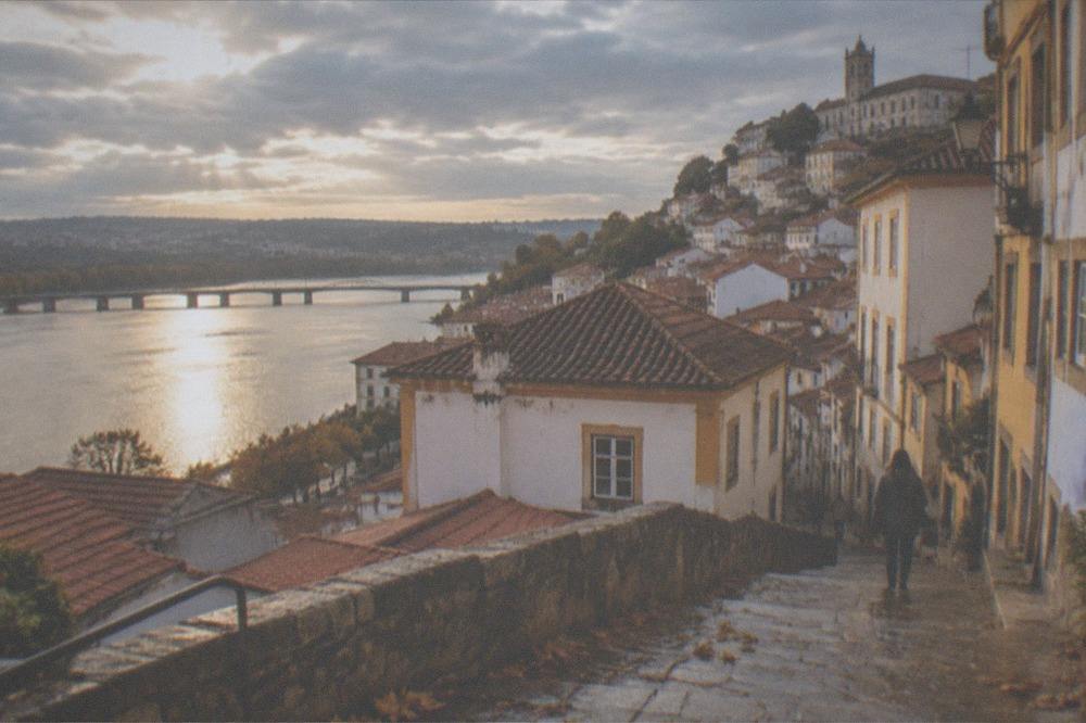 A sunny view over Coimbra rooftops toward the river with autumn light on the buildings