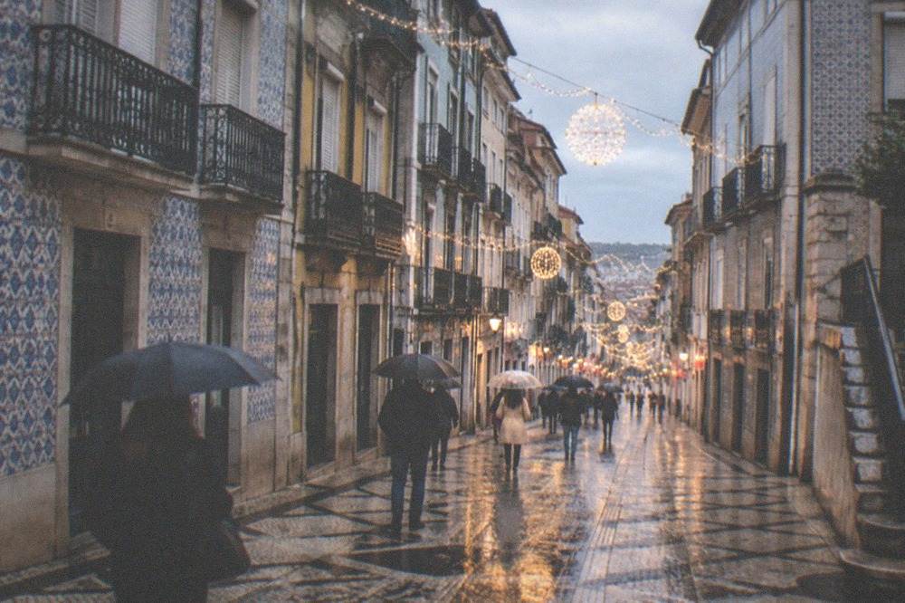 Festive lights strung across a shopping street in Coimbra's downtown at dusk in December