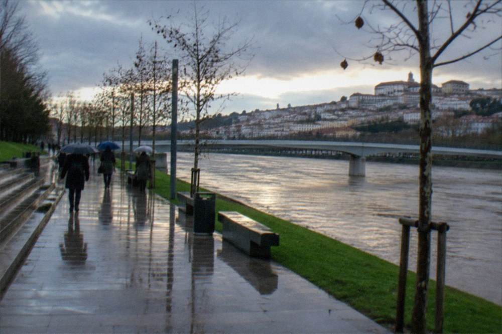 The Mondego riverside path in Coimbra under clearing skies after winter rain