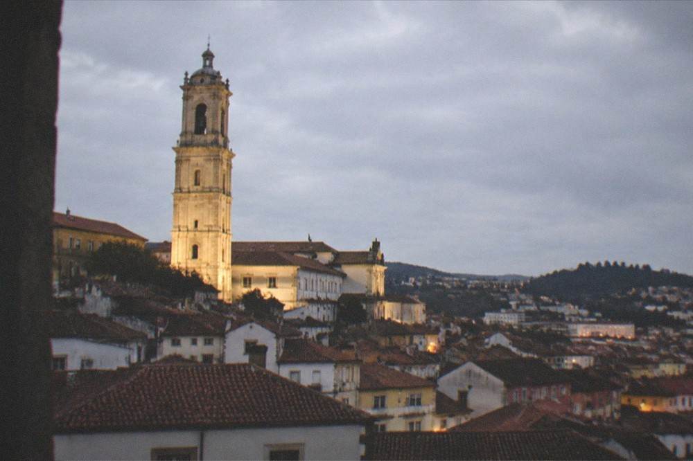 A night view over Coimbra's rooftops with the university tower lit above the city
