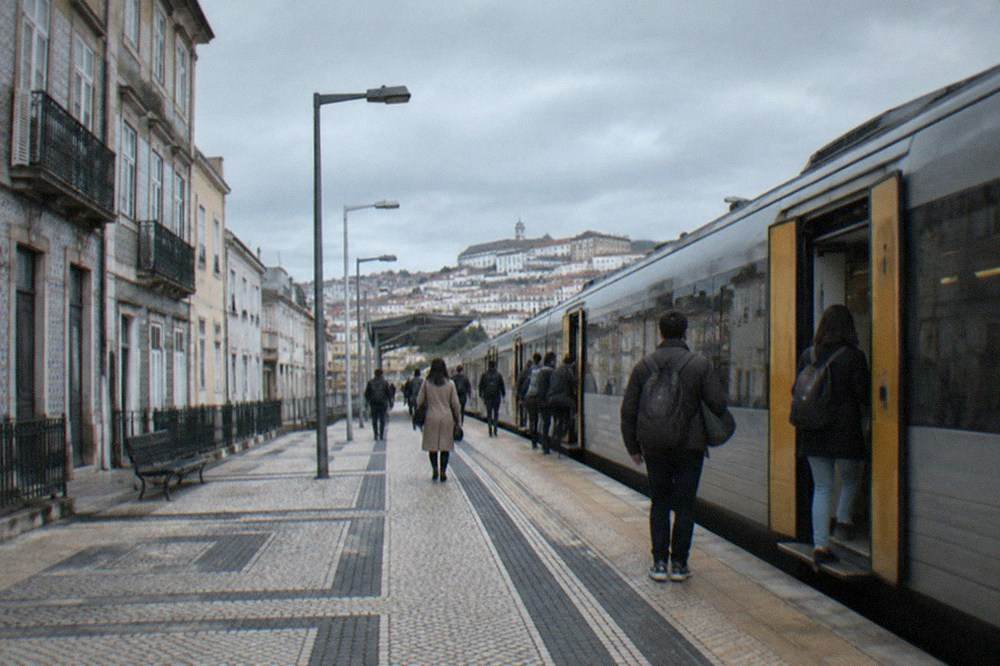 A regional train standing at a Portuguese station platform with passengers boarding