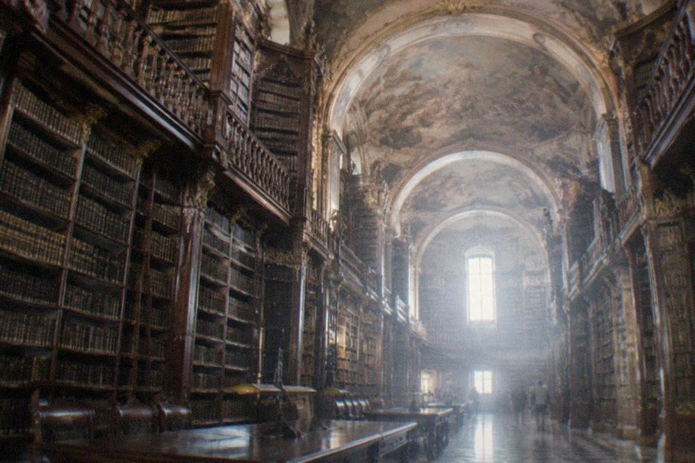 The baroque interior of the Joanina Library with tall wooden bookshelves and painted ceilings