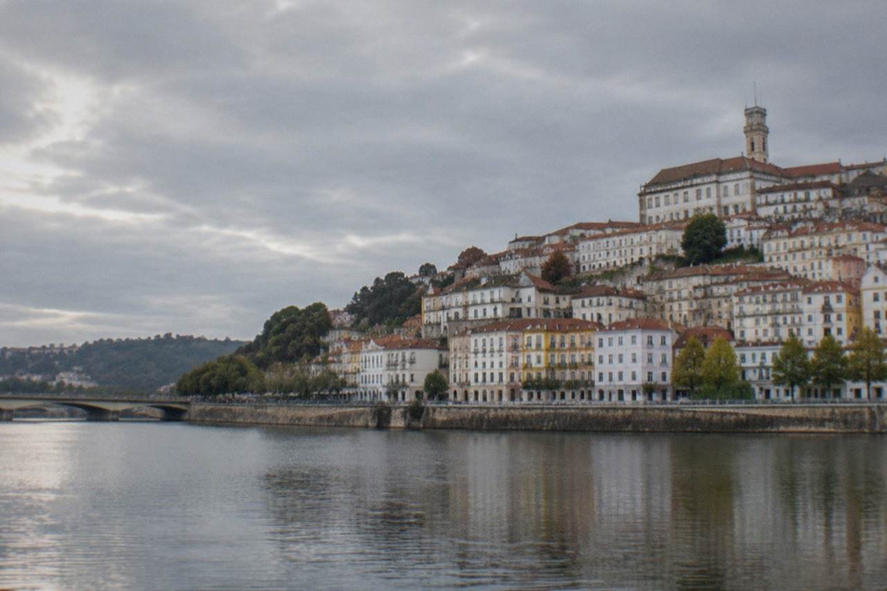The hillside of Coimbra, Portugal seen from across the River Mondego, with the university tower rising above the old town rooftops.
