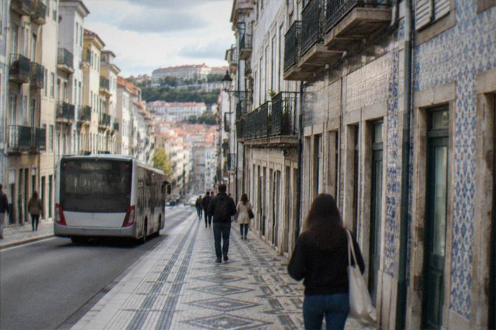 A bus and pedestrians on a street in Coimbra's lower town