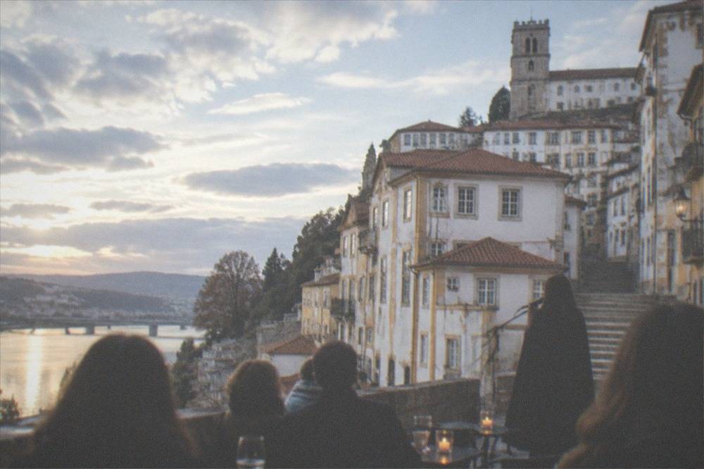 An audience seated at small candlelit tables listening quietly to a singer in a dark cape