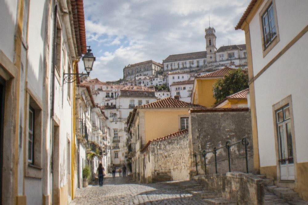 A steep cobbled street in Coimbra's old town climbing toward the university buildings