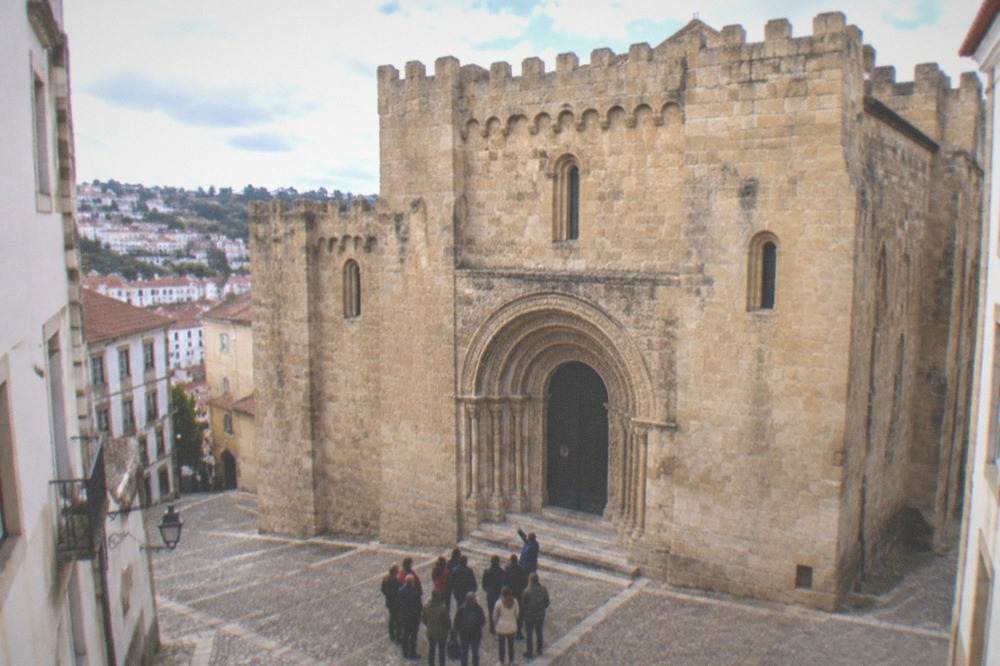A guide showing a small group the carved portal of the Sé Velha in Coimbra