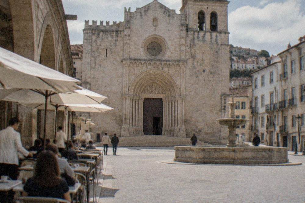 Waiters in white jackets serving coffee at marble tables inside a vaulted stone café room