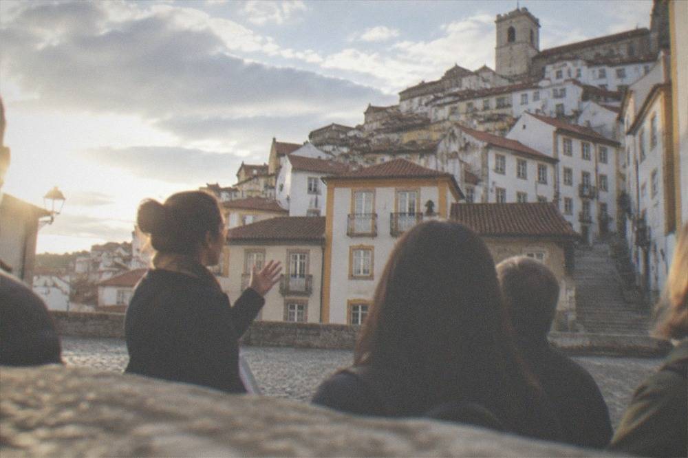 Tour guide speaking to a small group in a cobblestone square in old Coimbra