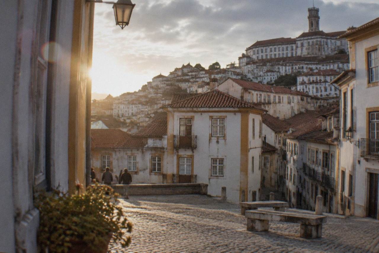 Cobbled square in central Coimbra with the old university buildings rising on the hill above the city
