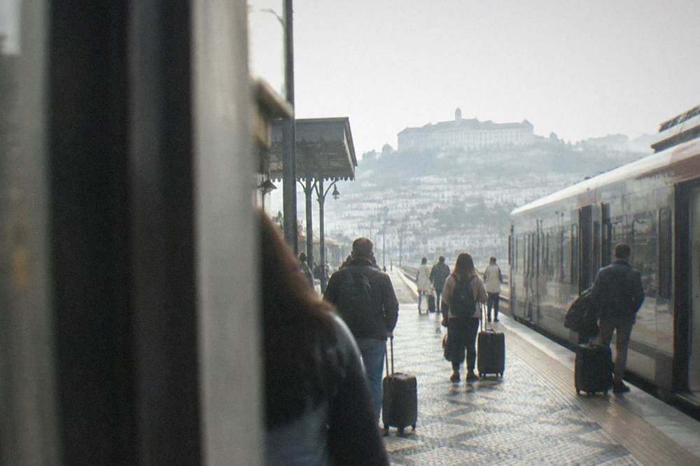 Railway platform in Coimbra with a train at the station and passengers waiting with luggage