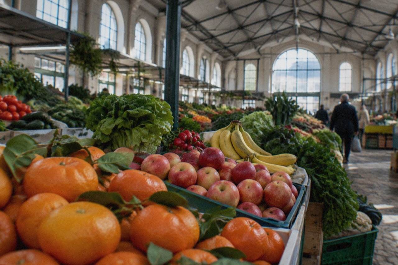 A covered market hall in Coimbra with stalls of fresh fruit and vegetables under a high ceiling