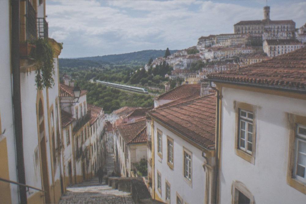 A long-distance train travelling through green countryside in central Portugal