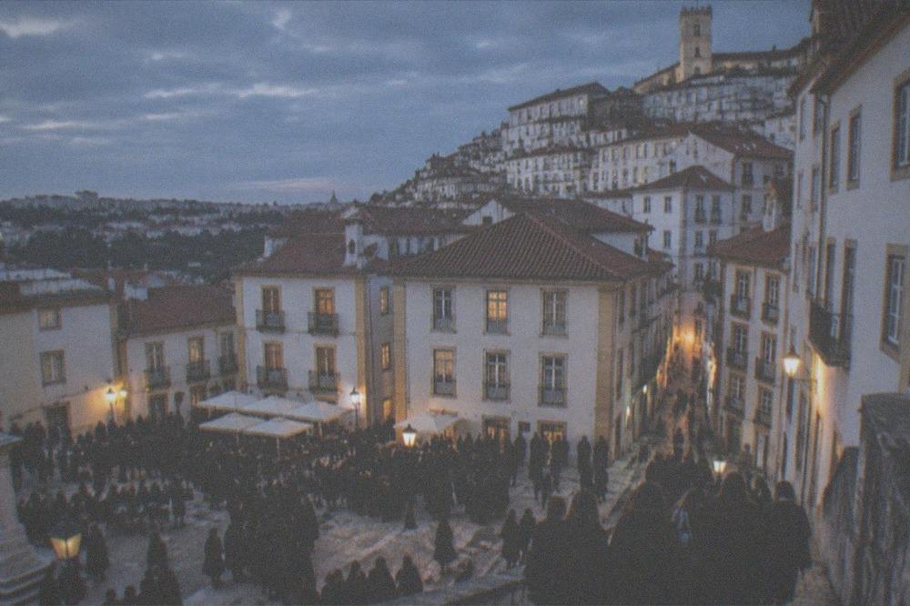 A crowd of students in black capes filling a Coimbra square during the May festival season