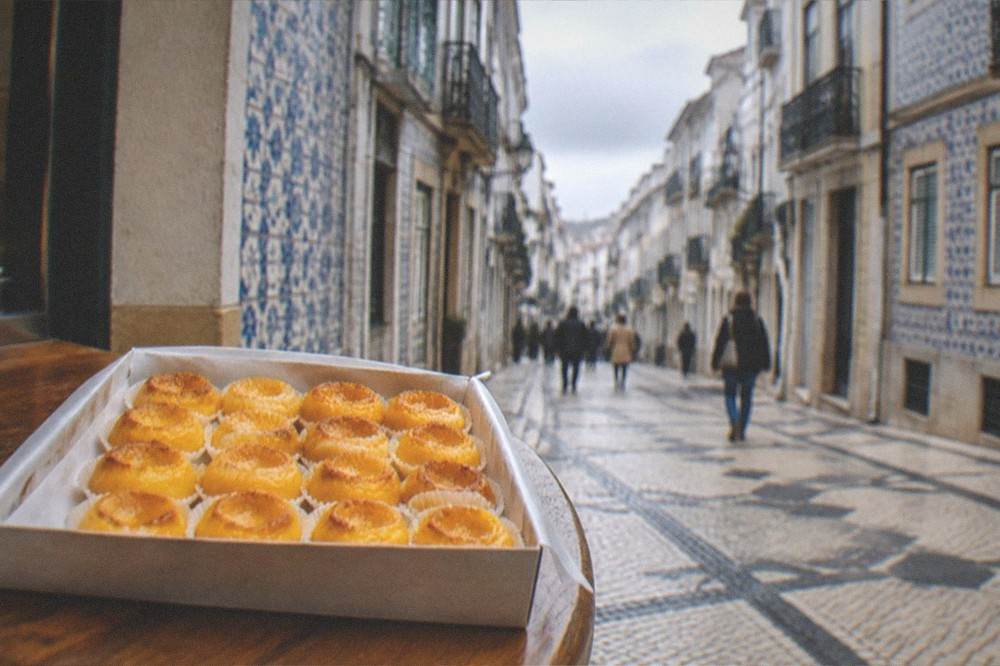 A box of small traditional egg-yolk sweets in paper wrappers on a wooden counter